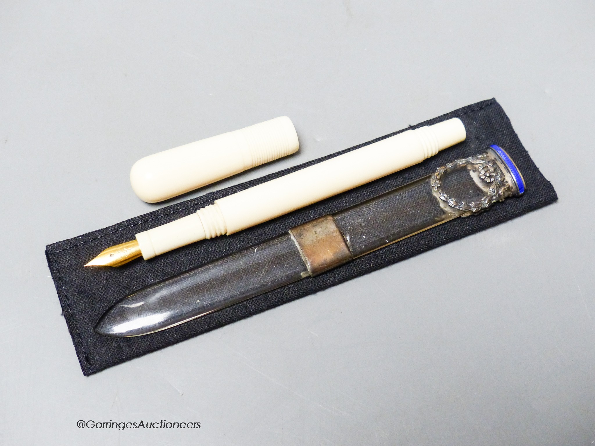 An early 20th century ivory eye dropper pen and an enamelled white metal mounted paperknife